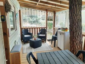 a porch with chairs and a table and a tree at Bonne anse plage in Les Mathes