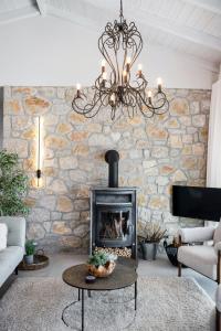 a stone fireplace in a living room with a chandelier at Grey Sea View Estate - Luxury Villas with Private Pool & Plunge Pool in Katouna