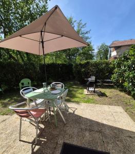 a table and chairs with an umbrella on a patio at Le Cocon Litois in Lit-et-Mixe