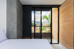 a bedroom with a white bed and a large window at Hotel Distrito 70 Living in Medellín