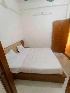 a bedroom with a bed with white sheets at Hotel King's Residency in Narendranagar