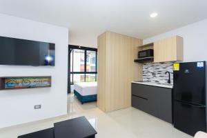 a kitchen with a black refrigerator and a bedroom at Hotel Distrito 70 Living in Medellín