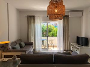 a living room with a couch and a television at Apt H - Beach Village in Olhos de Água +29 photos