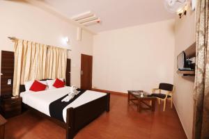 a hotel room with a bed with red pillows at JK Golden Embassy in Mysore