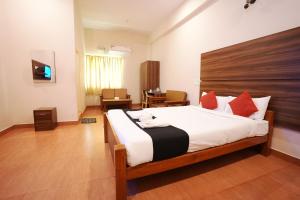 a bedroom with a large bed with red pillows at JK Golden Embassy in Mysore