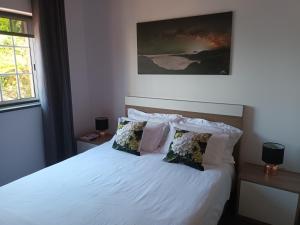 a bedroom with a bed with white sheets and pillows at Casinhas in Praia do Almoxarife