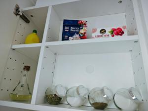 a white shelf with some bowls and a bottle at ArSa in Ventspils +18 photos