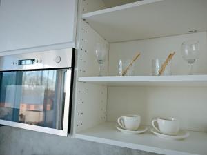 a kitchen with white shelves and cups and glasses at ArSa in Ventspils