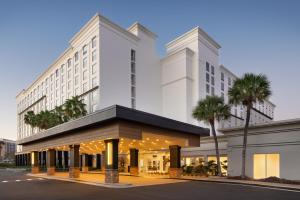 a large white building with palm trees in front of it at Courtyard by Marriott across Universal Orlando in Orlando