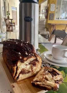 a loaf of bread on a cutting board next to a cup at CAMALEÃO Ecopousada Ltda in Linhares