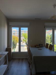 a dining room with a table and chairs and windows at Lamayade in Arcachon