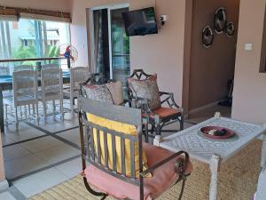 a living room with chairs and a tv on the wall at CosyNest Apartment in Cap Malheureux