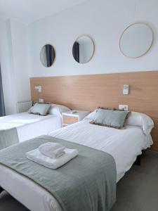 two beds in a room with two mirrors on the wall at Iberflat Apartamentos Marina Suites in Grao de Castellón