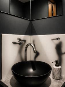 a black sink in a bathroom with birds on the wall at Jacuzzi Loft in the Center of Riga in Riga