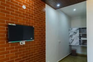 a flat screen tv hanging on a brick wall at Baatuli Homestay in Nainital