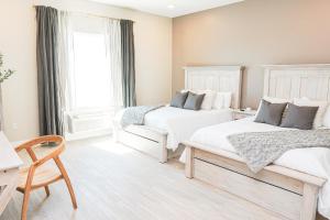 a white bedroom with two beds and a chair at Hotel Whiskey in Long Beach in Long Beach