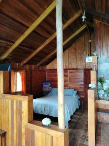 a bedroom with a bed in a wooden cabin at Reserva Natural Cerro Alto in Empalme