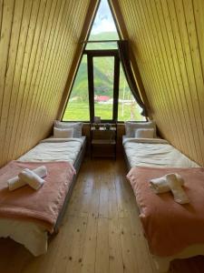 two beds in a room with a large window at River View Cabin Kazbegi in Kazbegi