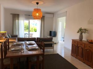 a dining room and living room with a table and chairs at Apt H - Beach Village in Olhos de Água