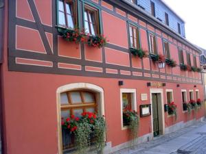 a red building with flowerpots and windows on a street at Gästezimmer Stadtmitte im EG in Bad Schandau