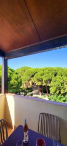 a table on a balcony with a view of trees at Duplex Camargue Village in Le Grau-du-Roi