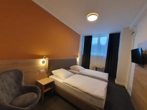 a hotel room with a bed and a chair at Akdeniz Pension in Ludwigsfelde