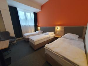 a hotel room with three beds and a chair at Akdeniz Pension in Ludwigsfelde