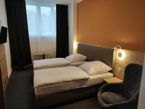 a hotel room with two beds and a chair at Akdeniz Pension in Ludwigsfelde