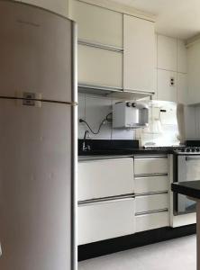 a kitchen with white cabinets and a refrigerator at Quarto Sol in Brasília