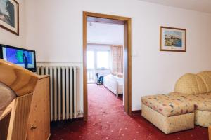 a room with a bedroom with a bed and a television at Hotel Schönwies in Trodena