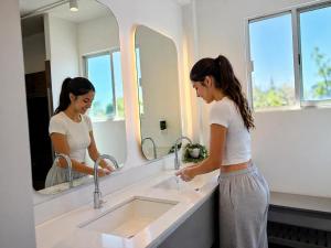 a woman standing in front of a sink in a bathroom at Hostal Nube Mia Guadalajara in Guadalajara +5 photos