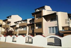 a white fence in front of a building at Siana House in Ravda