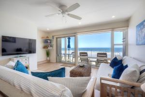 a living room with a couch and a television with a view of the ocean at Oceanfront 2BR - Private Patio - Steps to Beach in Carlsbad