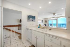 a white kitchen with a sink and a window at Oceanfront 2BR - Private Patio - Steps to Beach in Carlsbad