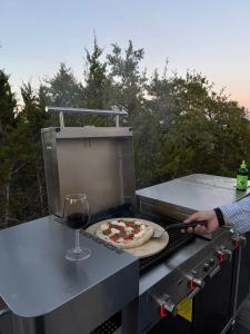 a person cooking a pizza on a grill with a glass of wine at Lagom Retreat in Dripping Springs