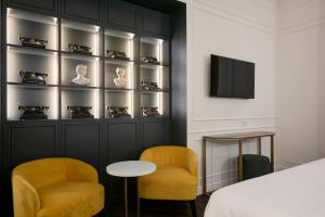 a bedroom with a bed and two chairs and a tv at Majestic Palace Hotel in Sant'Agnello