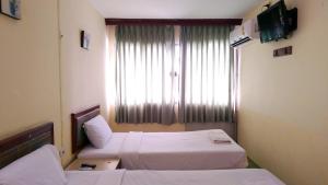 a hotel room with two beds and a window at โรงแรมวัฒนาตรัง in Trang
