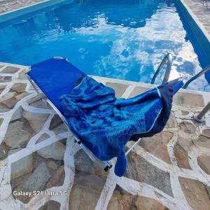 a blue folding chair next to a swimming pool at Blue Cactus village center in Agia Pelagia