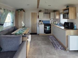 a kitchen and living room with a couch and a table at Pines 15 in Porthcawl