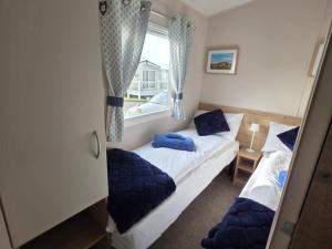 two beds in a small room with a window at Pines 15 in Porthcawl +13 photos