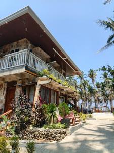 a building with a balcony on a beach with palm trees at Ocean View and Beach Access Rustic Stone House in Bolinao
