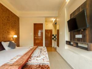 a bedroom with a bed and a flat screen tv at Art-llers Homestay in Dharmsāla