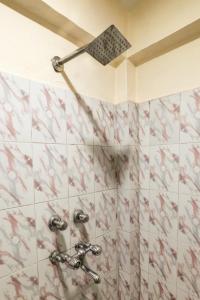 a shower in a bathroom with red and white tiles at Art-llers Homestay in Dharmsāla