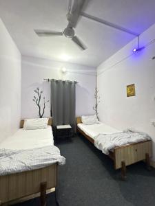 two twin beds in a room with a curtain at HOTEL O DEV RAJ Homestay in Rishīkesh