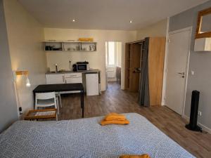 a bedroom with a bed and a table and a kitchen at Studio tout équipé calme et lumineux Roubaix in Roubaix