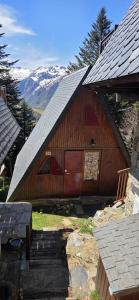 a large wooden barn with a door and mountains in the background at Chalet Fontaine 54 in Ustou