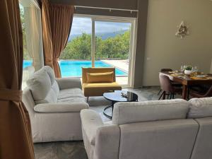 a living room with white furniture and a view of a pool at Villa Iulia Hills in Fiumefreddo di Sicilia