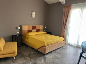a bedroom with a yellow bed and a chair at Villa Iulia Hills in Fiumefreddo di Sicilia