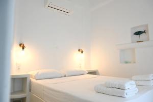 a white bedroom with two white towels on a bed at Sto Faro - Green in Kithnos