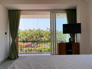 a bedroom with a bed and a balcony with a television at Mahadeva Residency in Trivandrum
